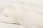 The image is a close-up of a white fabric, possibly a sheer or sheer-like material, with a soft, flowing texture.