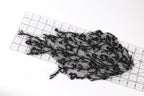 a piece of black lace with intricate patterns, laid out on a transparent ruler.