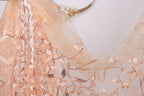 a delicate, peach-colored fabric with a floral pattern, including leaves and sequins. The fabric appears to be a sheer or sheer-like material, with a soft and delicate texture.