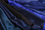 A close-up view of a variety of colorful satin fabric, including shades of blue, black, and brown, arranged in a visually appealing manner.