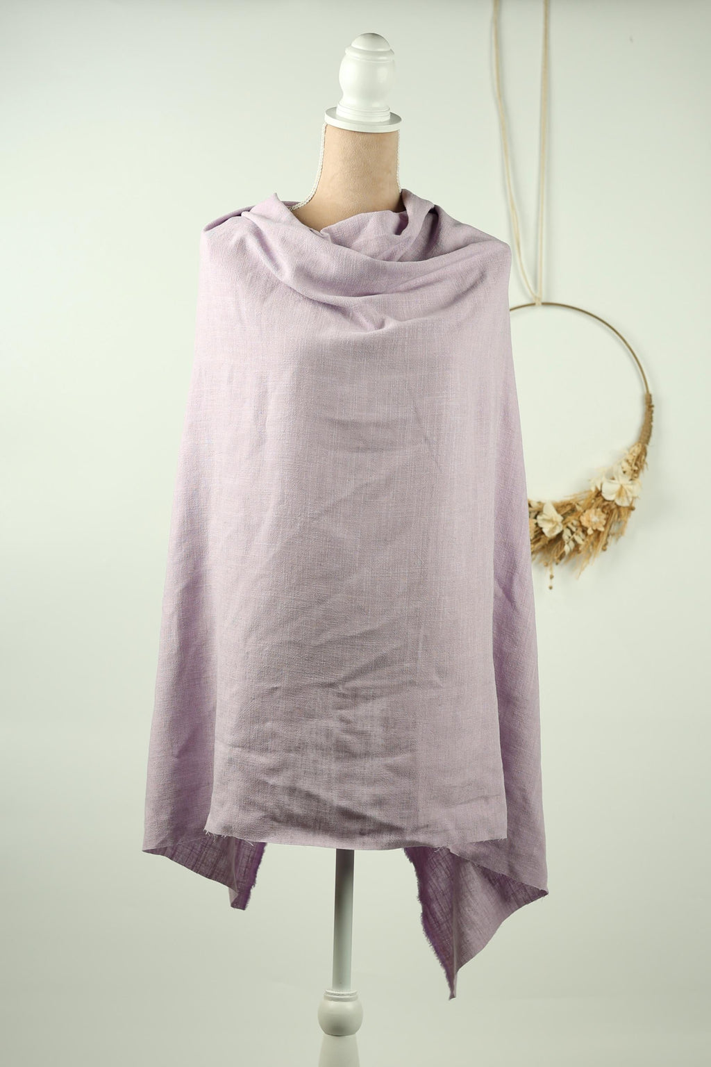 A mannequin wearing a lavender-colored scarf stands against a white background.