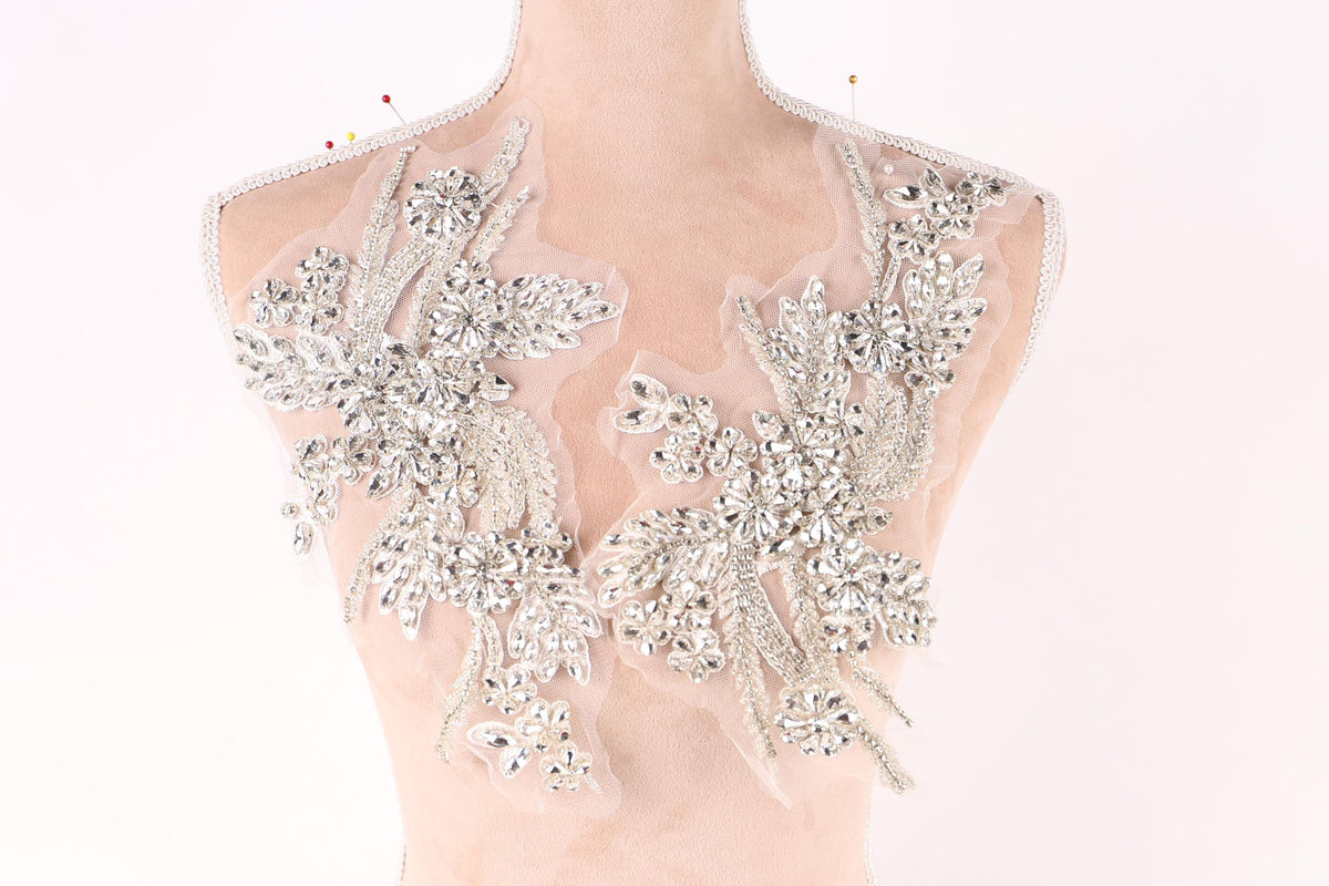 A mannequin wearing a dress with intricate, sparkling embellishments on the shoulders and neck area.