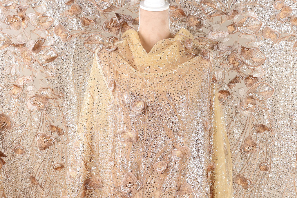 a mannequin wearing a gold and beige sequined dress with a floral pattern.