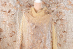 a mannequin wearing a gold and beige sequined dress with a floral pattern.