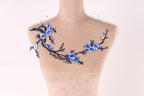 A mannequin with a floral design on its bust, featuring blue flowers and branches.