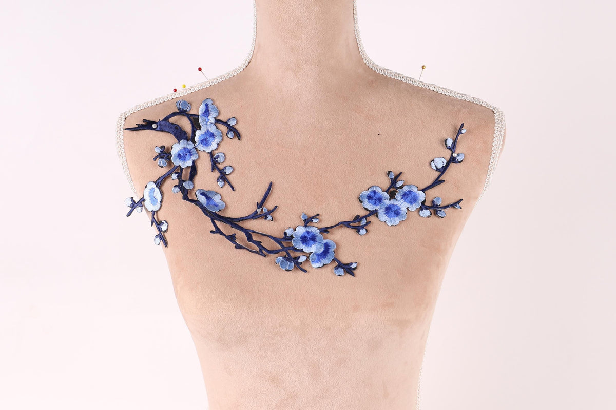 A mannequin with a floral design on its bust, featuring blue flowers and branches.