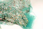a close-up view of a fabric with a floral pattern, featuring a mix of green and white colors.