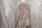 a mannequin wearing a shimmering, sequined dress with a floral pattern. The dress has a sheer back and long sleeves, creating a visually striking and elegant appearance.
