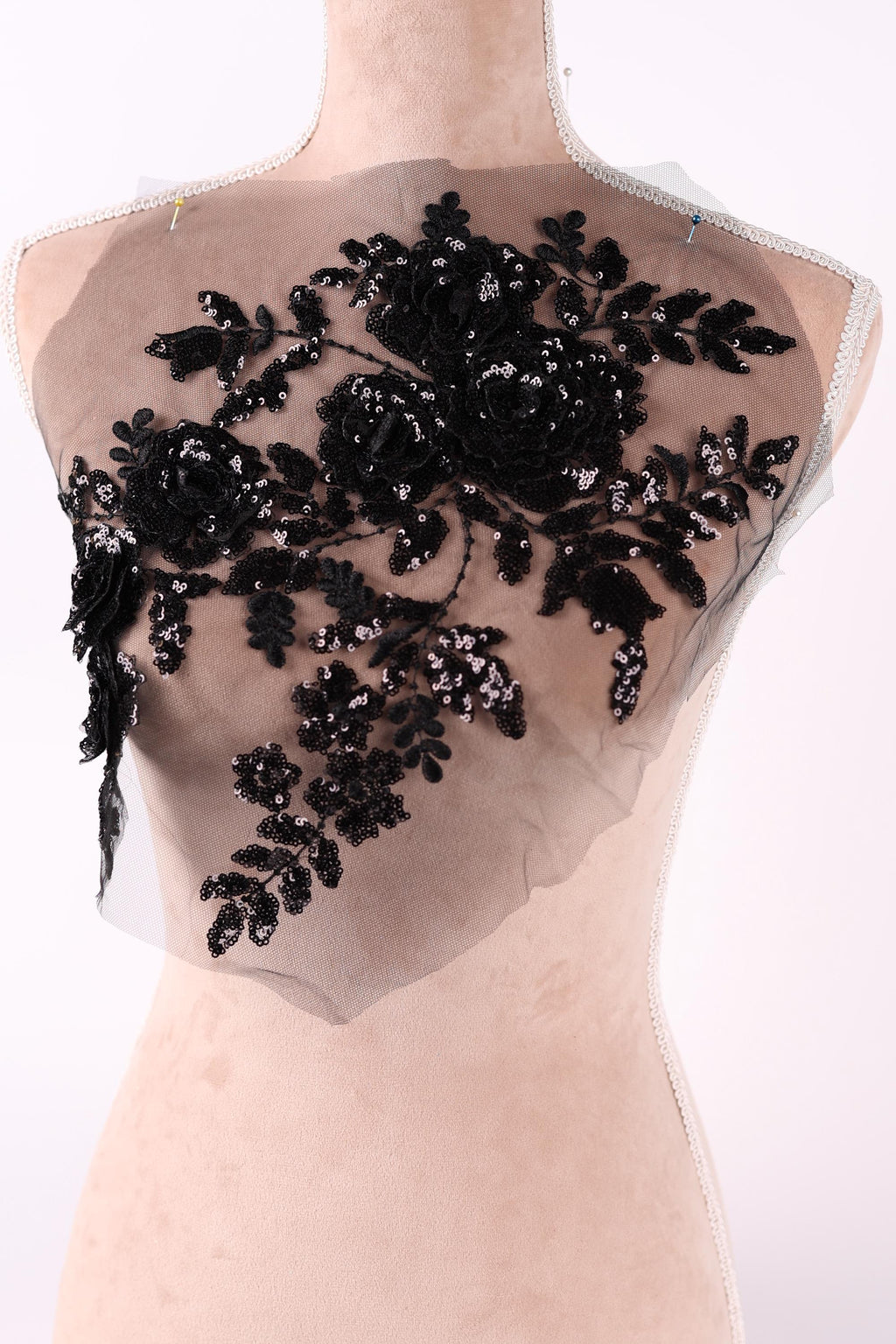 a close-up view of a delicate, black lace flower design on a light-colored fabric.