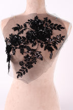 a close-up view of a delicate, black lace flower design on a light-colored fabric.