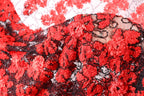 The image is a close-up of a fabric with a red and black floral pattern, featuring numerous small red flowers and black beads or sequins.