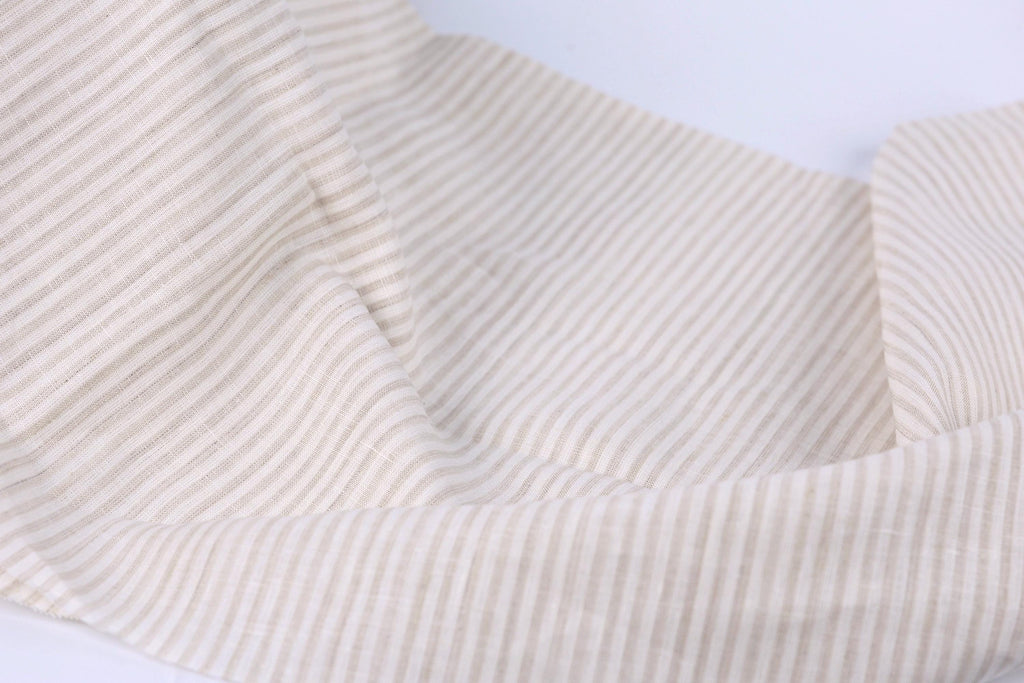 A close-up view of a fabric with horizontal stripes in various shades of beige and white.