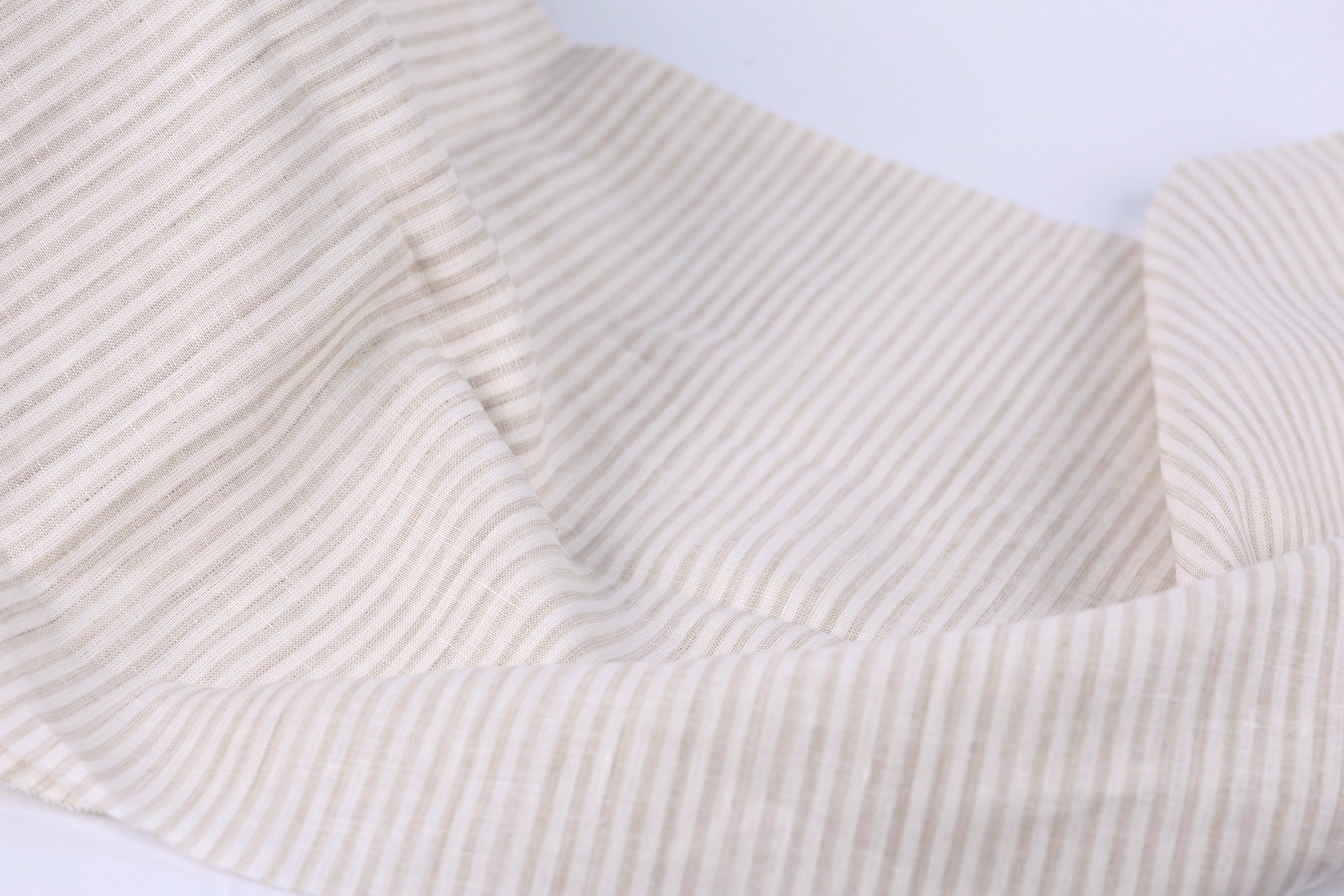 A close-up view of a fabric with horizontal stripes in various shades of beige and white.