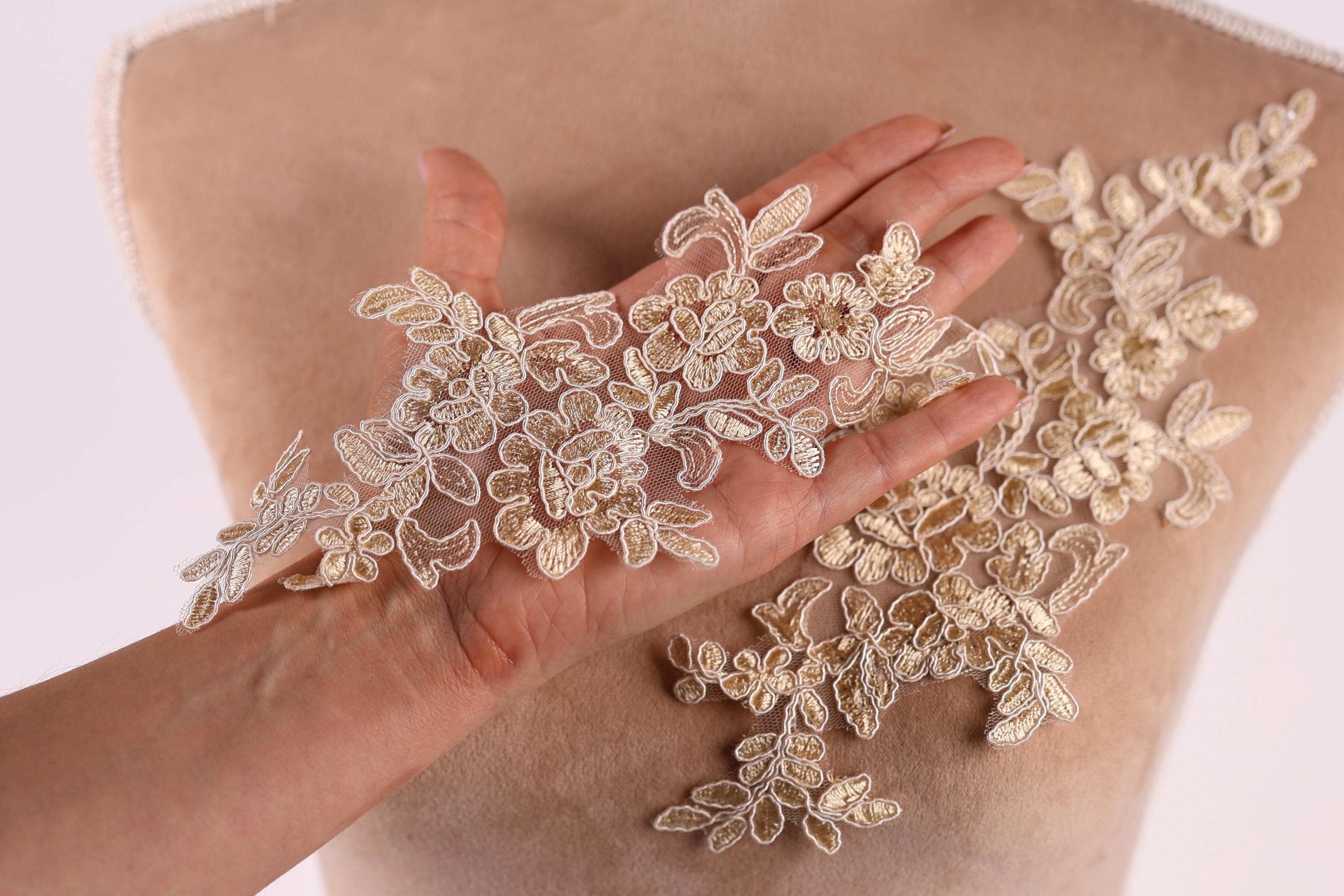 A hand is holding a piece of fabric with delicate, intricate lace-like patterns on it.