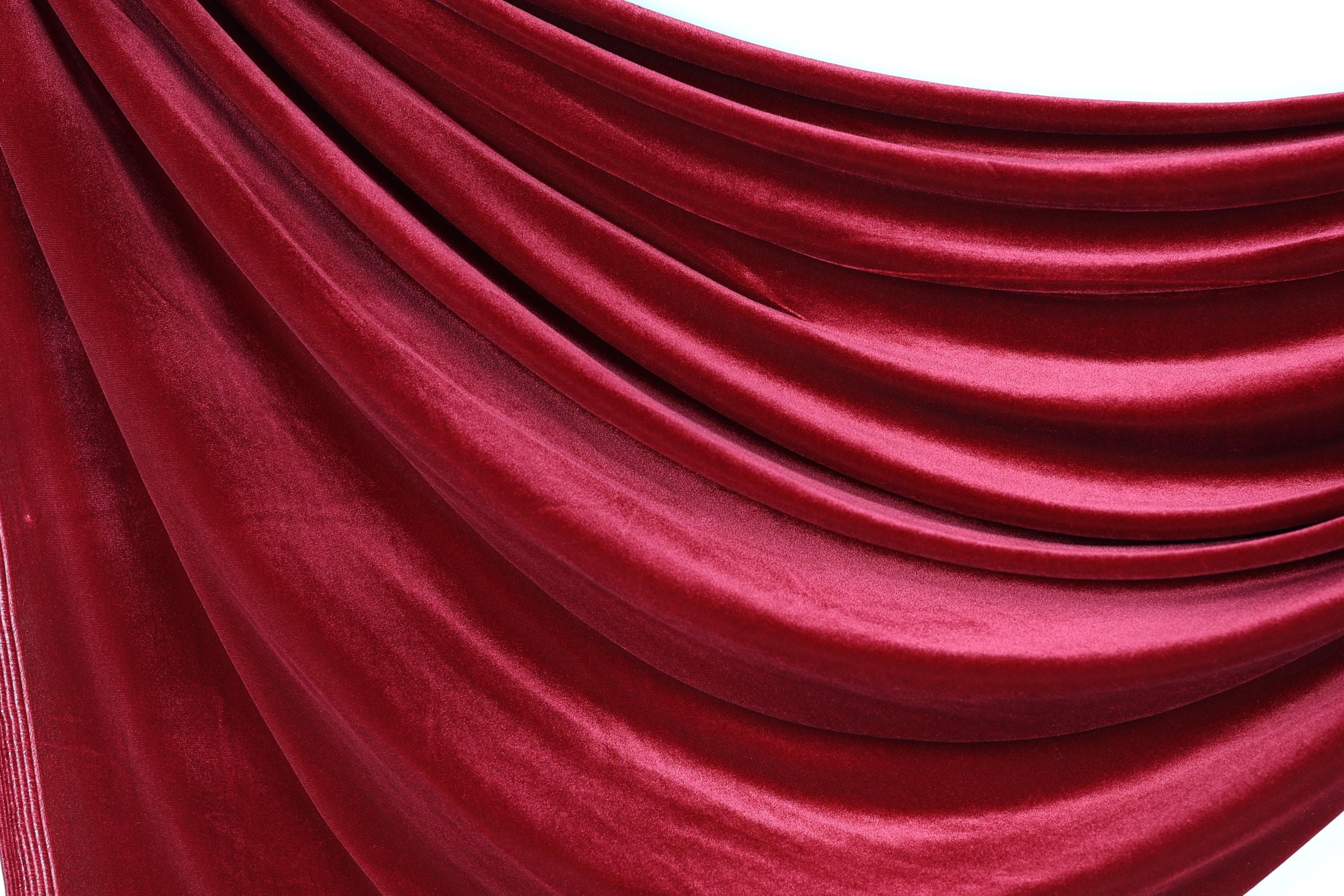 a close-up view of a red velvet curtain, with its folds and creases visible.