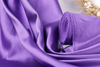 a close-up view of a purple fabric, possibly silk or satin, with a rolled-up end visible.