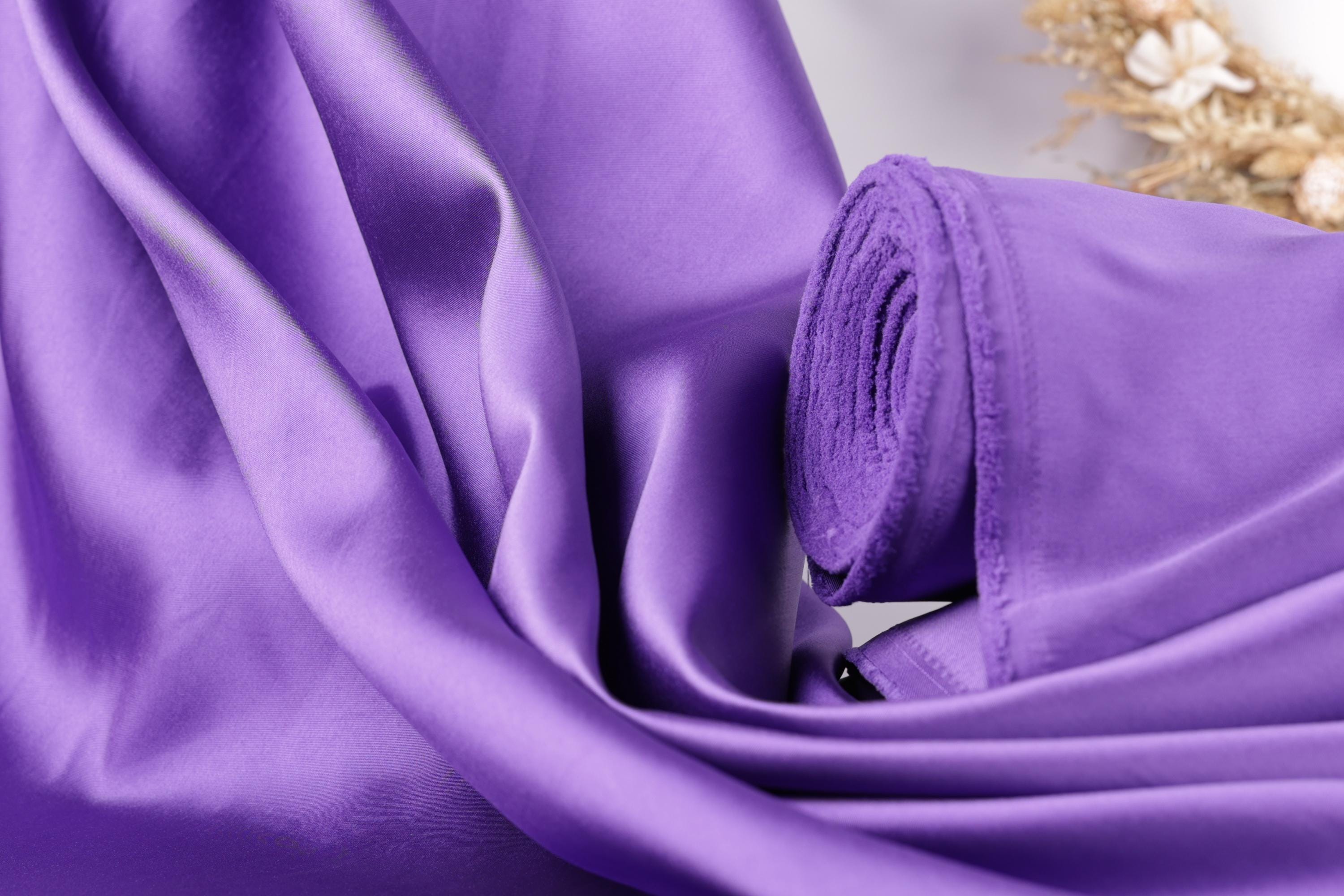 a close-up view of a purple fabric, possibly silk or satin, with a rolled-up end visible.