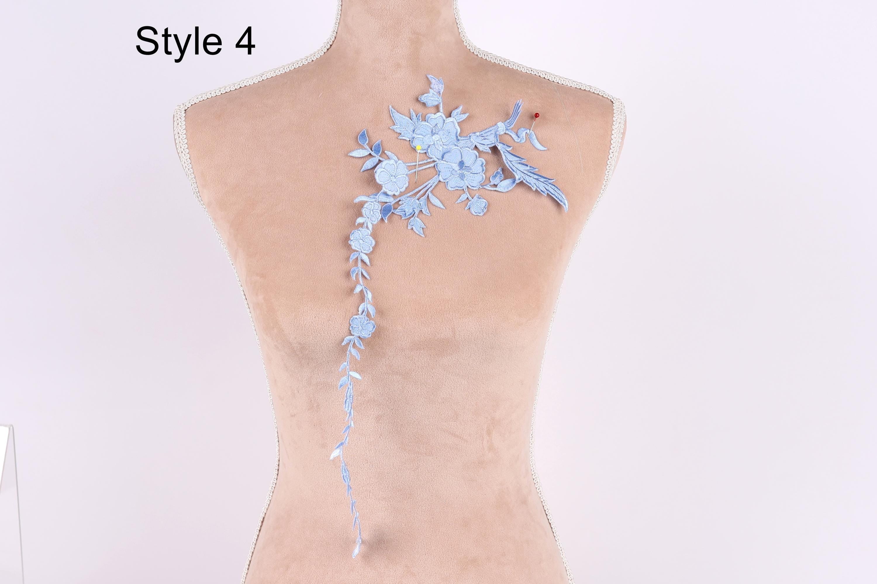 A mannequin with a blue floral embroidered on its back, featuring a long, delicate flower design.