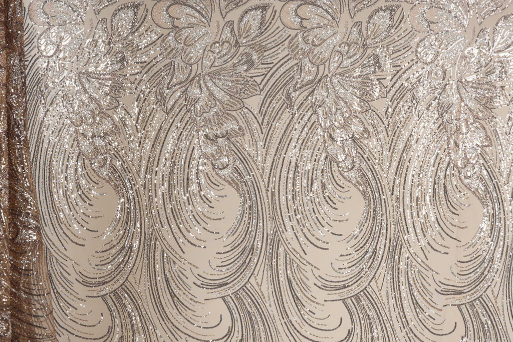 a close-up view of a fabric with a repeating pattern of swirls and lines in shades of brown and beige. The pattern appears to be made of sequin or glitter, giving it a shiny and textured appearance.