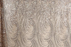 a close-up view of a fabric with a repeating pattern of swirls and lines in shades of brown and beige. The pattern appears to be made of sequin or glitter, giving it a shiny and textured appearance.