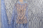a sequin fabric with a blue and silver pattern, hanging against a gray background.