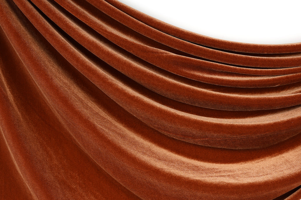 a close-up view of a brown, shiny fabric, possibly velvet, with a smooth, flowing texture.