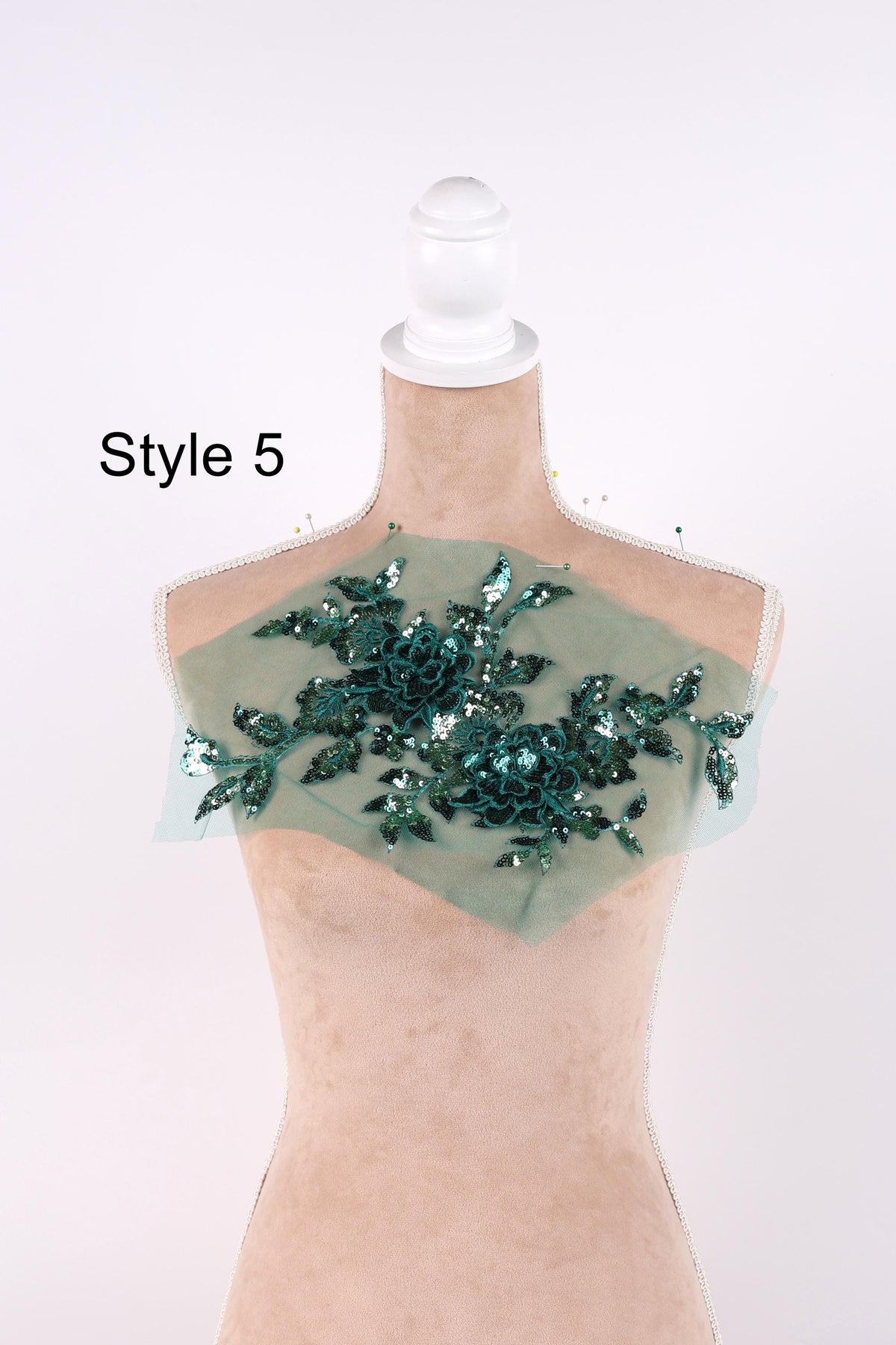 A mannequin with a decorative green leaf-like embellishment on its chest, which appears to be a piece of clothing or accessory.