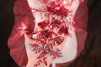 A close-up view of a hand adorned with a red and silver sequin design, featuring a floral pattern and a large flower-like element.