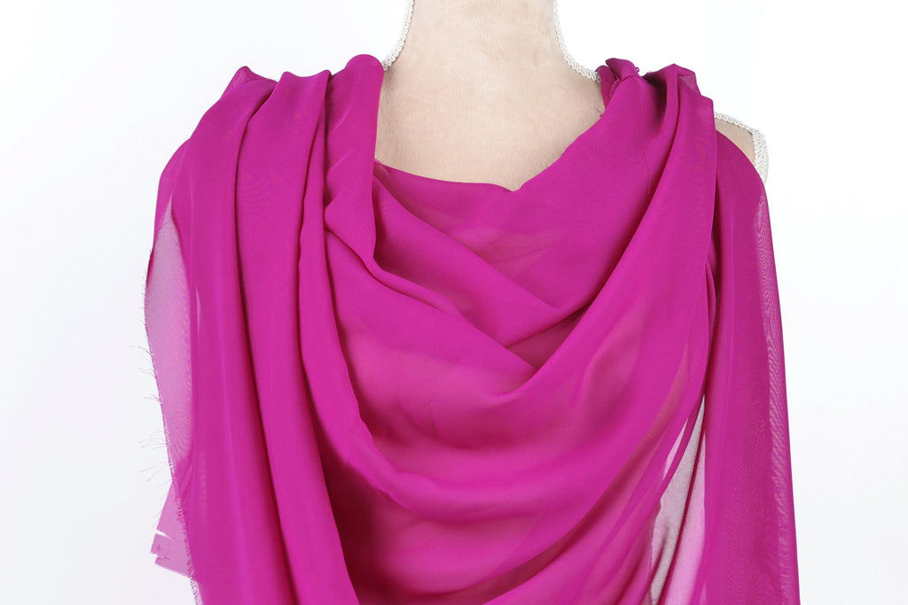 A mannequin wearing a vibrant pink chiffon scarf draped over its shoulder.