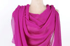 A mannequin wearing a vibrant pink chiffon scarf draped over its shoulder.
