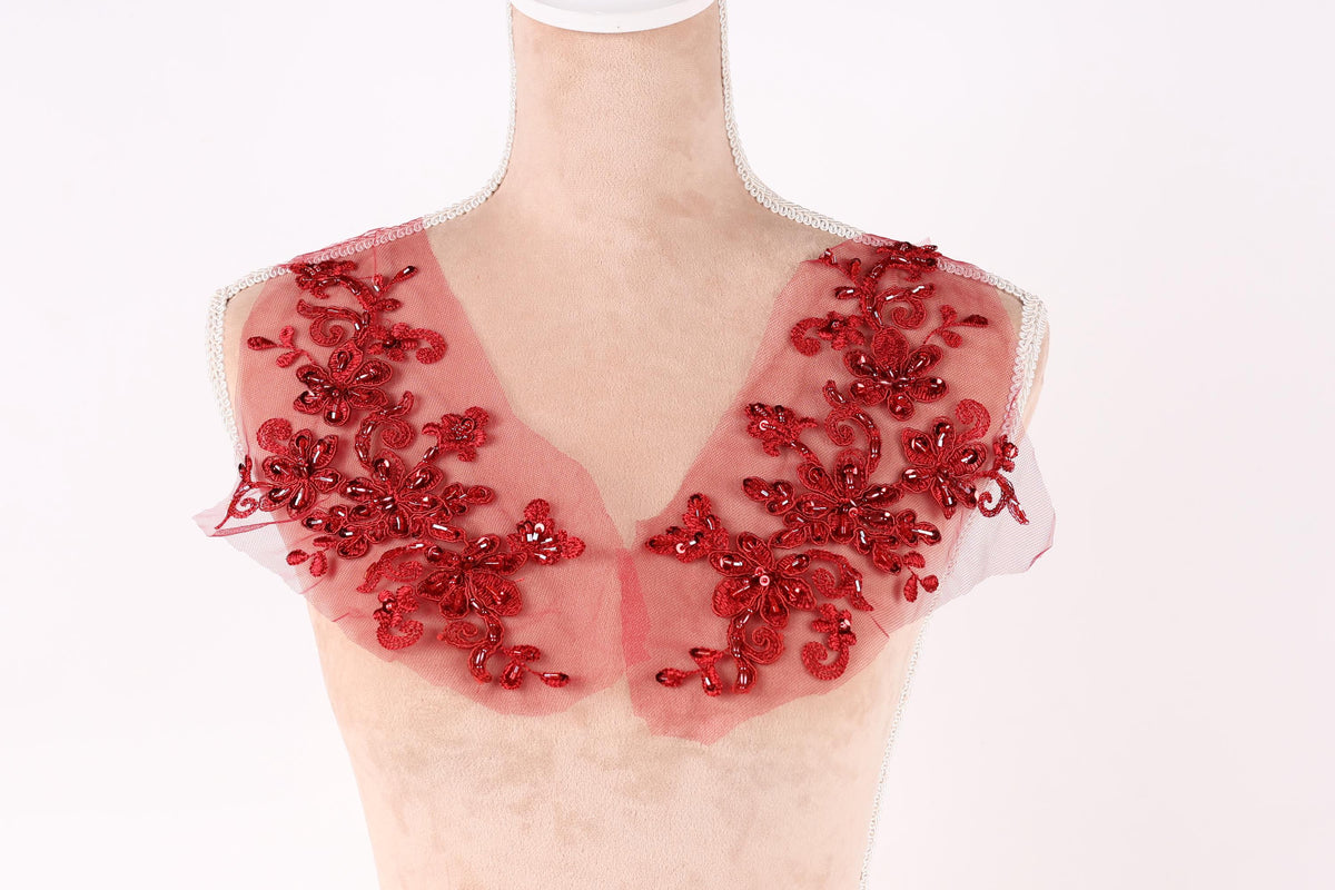A mannequin wearing a red, sheer collar with intricate floral embroidery.