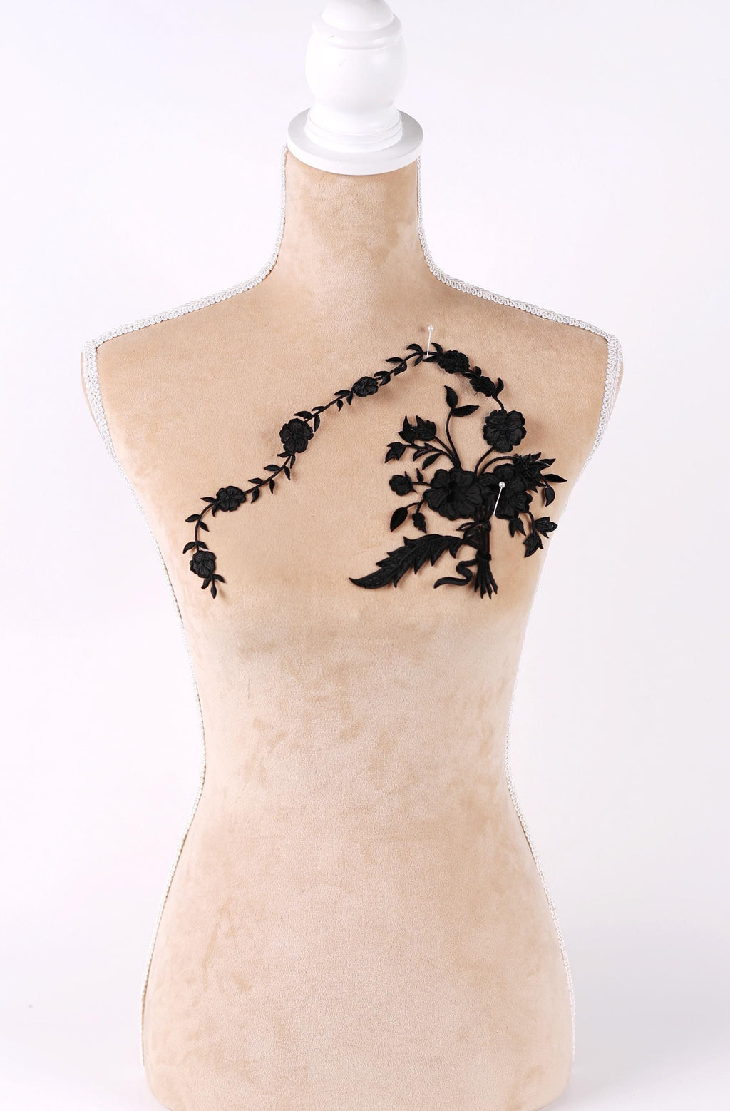 A mannequin with a beige body and a black floral embroidered on its chest.