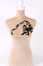 A mannequin with a beige body and a black floral embroidered on its chest.