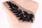 a close-up view of a delicate, black lace or sequin embellishment on the back of a mannequin or dress form.