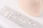 a close-up view of a ruler with a delicate floral pattern on it, placed next to a beige object.