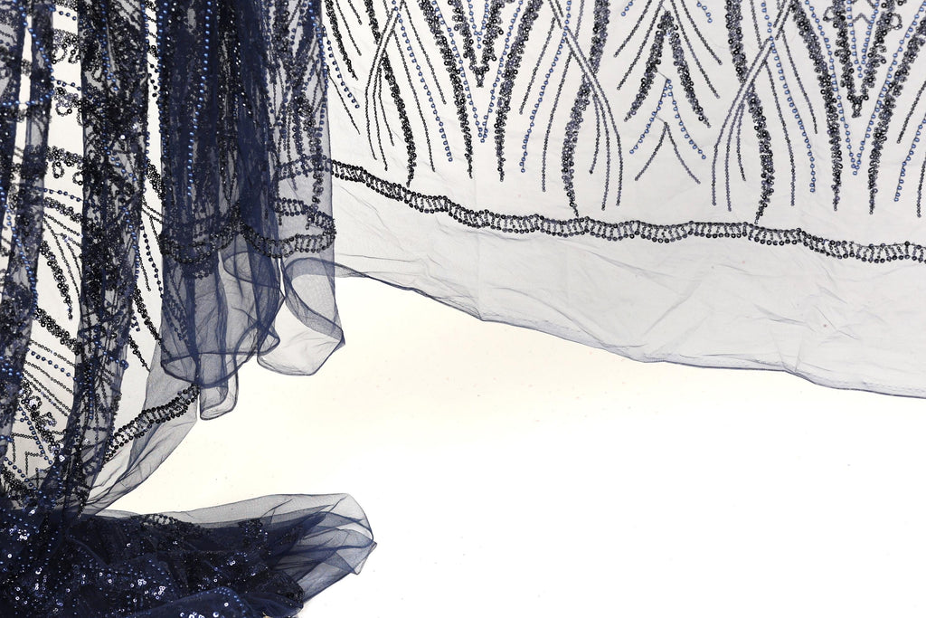 a close-up view of a piece of fabric with a dark blue and white color scheme, adorned with intricate patterns and designs. The fabric appears to be a sheer material, with a delicate and elegant appearance.