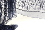 a close-up view of a piece of fabric with a dark blue and white color scheme, adorned with intricate patterns and designs. The fabric appears to be a sheer material, with a delicate and elegant appearance.