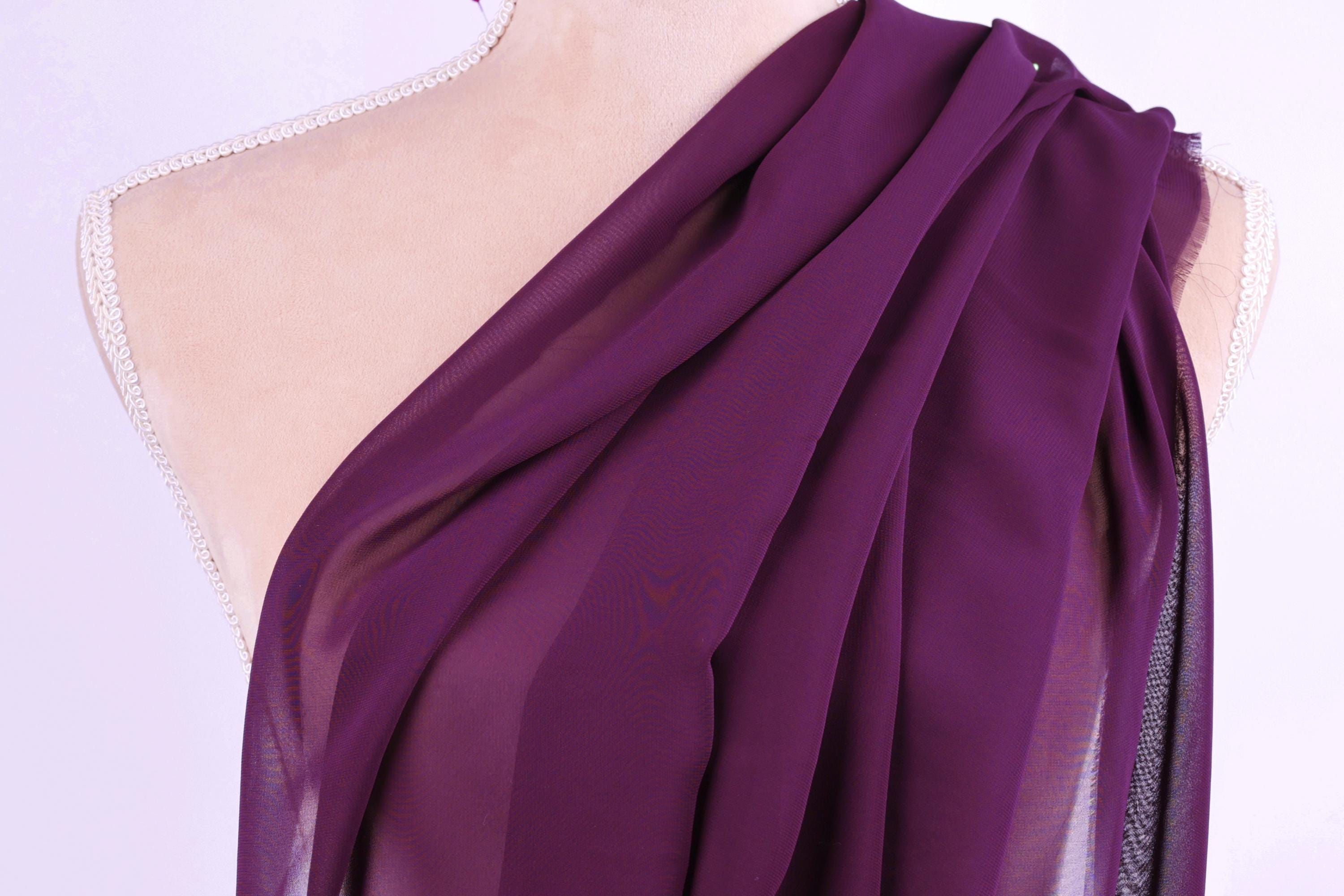 A mannequin wearing a purple draped garment with a flowing, draped appearance.