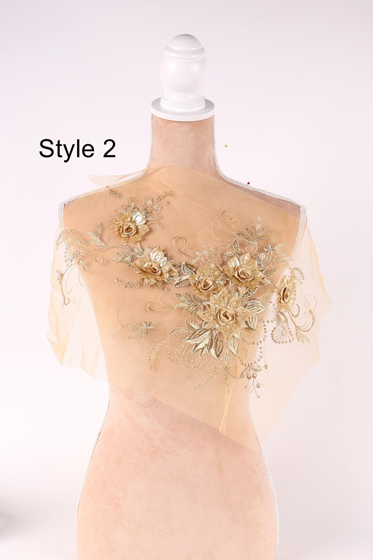 A mannequin wearing a gold-colored floral print dress with a sheer overlay.