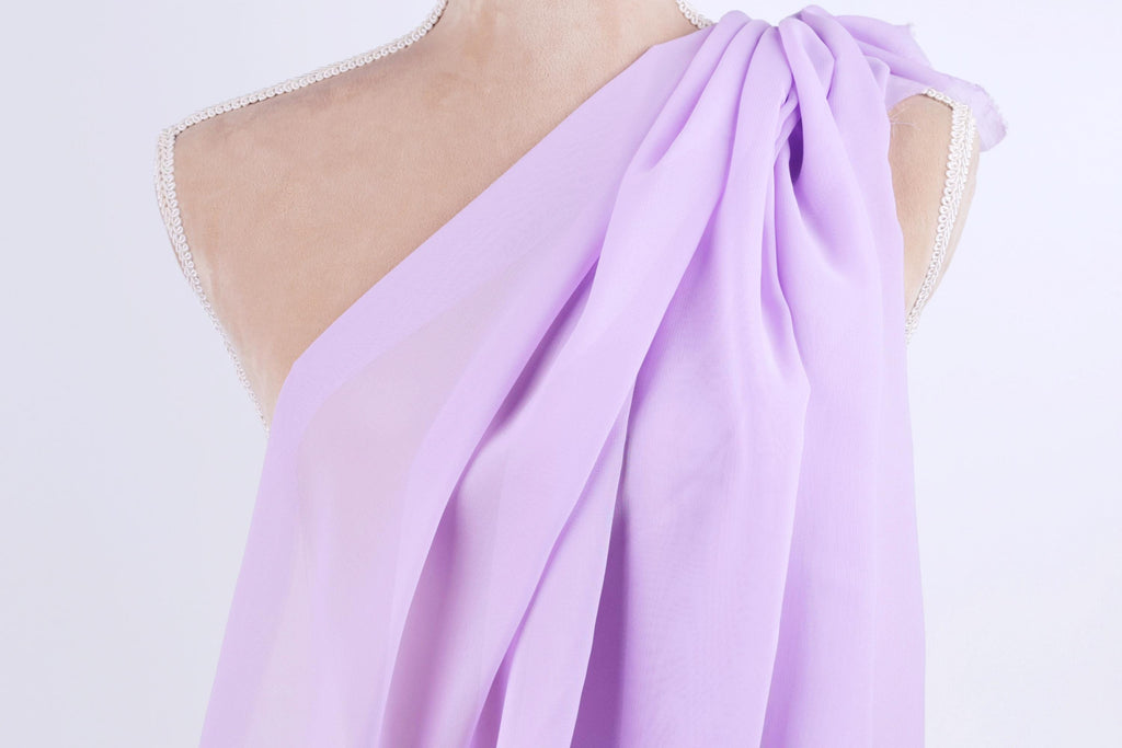 A mannequin wearing a purple draped dress with a flowing, draped design.