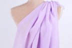 A mannequin wearing a purple draped dress with a flowing, draped design.