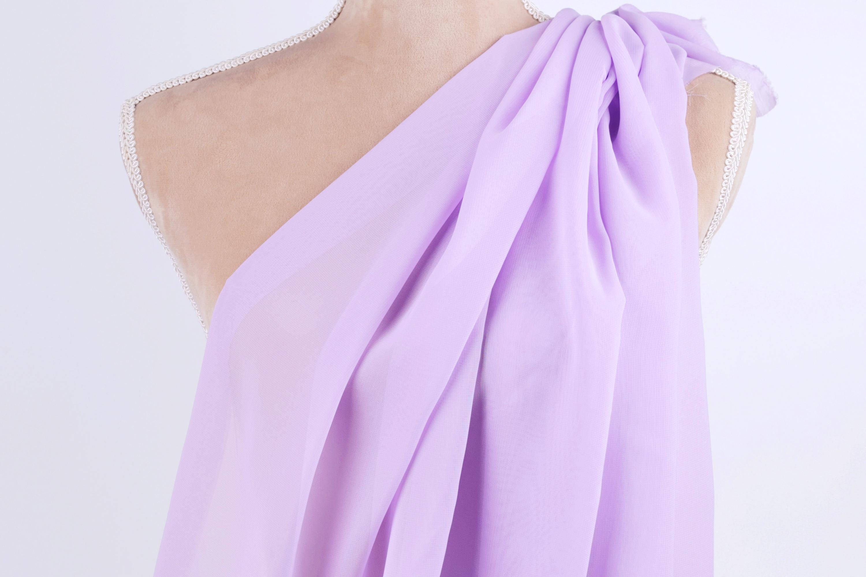 A mannequin wearing a purple draped dress with a flowing, draped design.