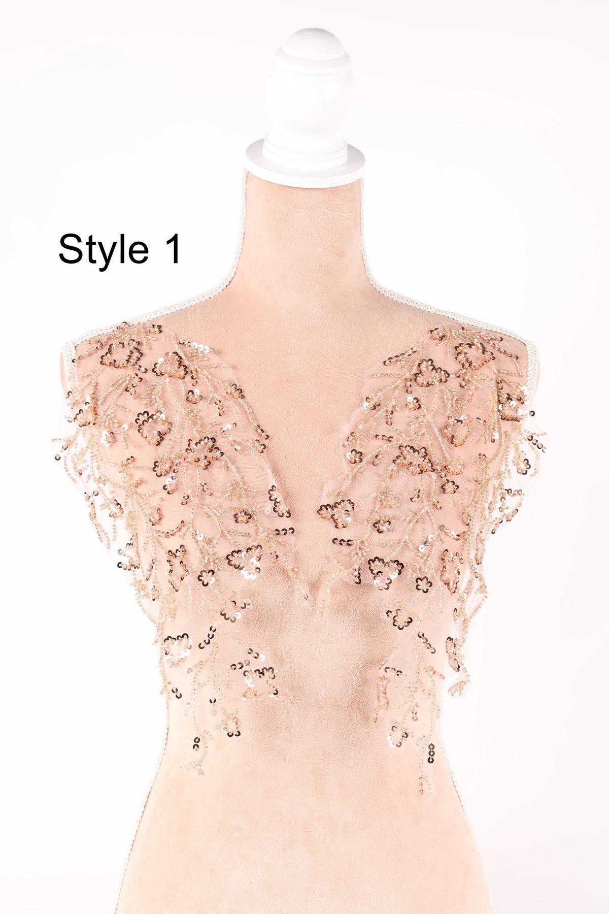 A mannequin wearing a dress with a floral pattern and sequin embellishments on the shoulders and chest area.