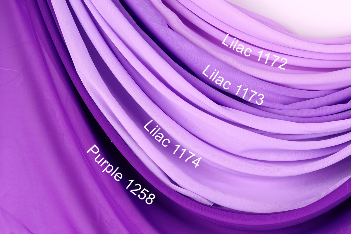 a close-up view of a fabric with purple and lavender hues, arranged in a gradient. The fabric appears to be a sheer material, with the colors transitioning smoothly from purple to lavender. The fabric is labeled with the names of the colors, including "Lilac 1172", "Lilac 1173", "Purple 11258", and "Purple 1258".
