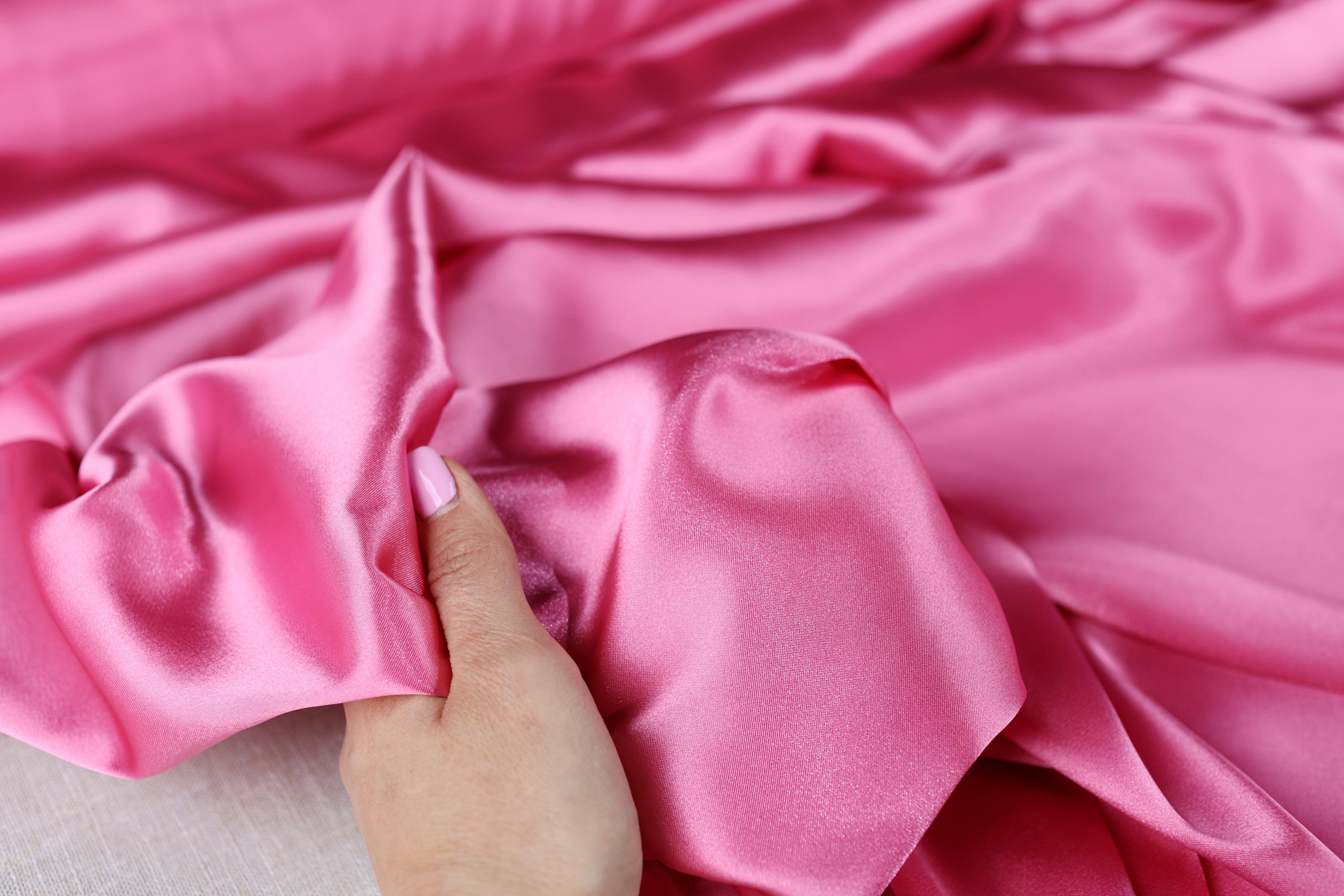a person is holding a pink satin material