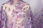 a mannequin wearing a sheer, purple, and pink sequin fabric draped over its body.