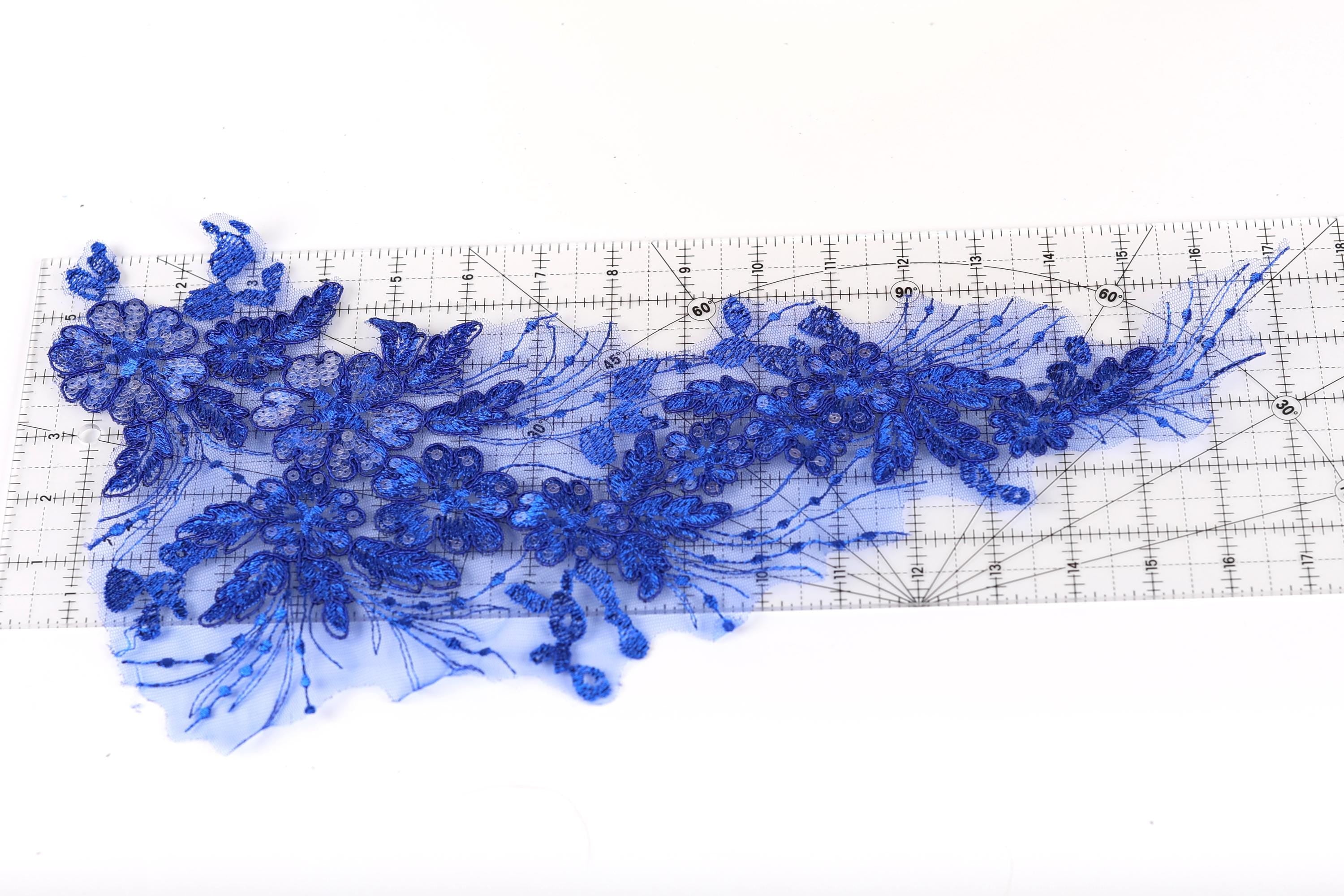 a close-up view of a blue sequin flower design on a ruler, with the ruler providing a scale reference for the size of the flower.