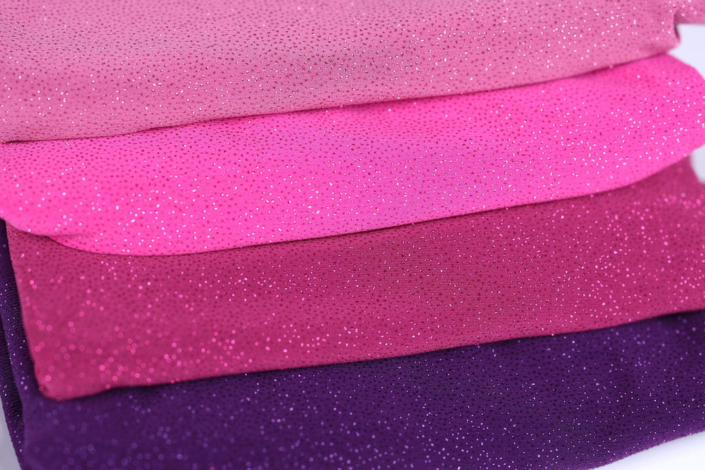 A close-up image of a pile of fabric with a glittery texture, featuring a variety of colors including pink, purple, and purple.