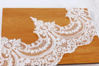 a close-up view of a delicate, intricate white lace fabric with a floral pattern, resting on a wooden surface.
