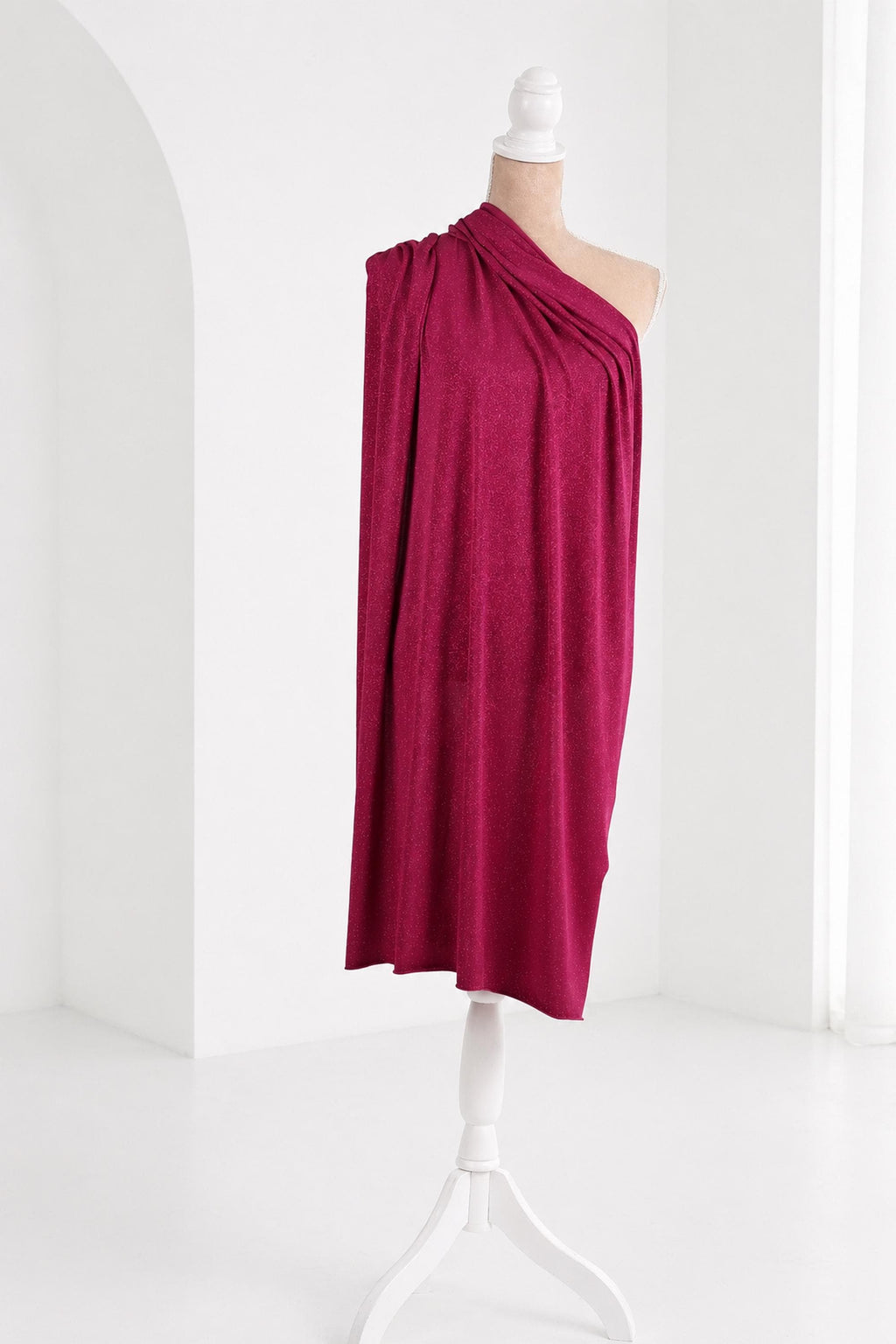 A mannequin wearing a vibrant red one-shoulder dress stands on a white pedestal against a white background.